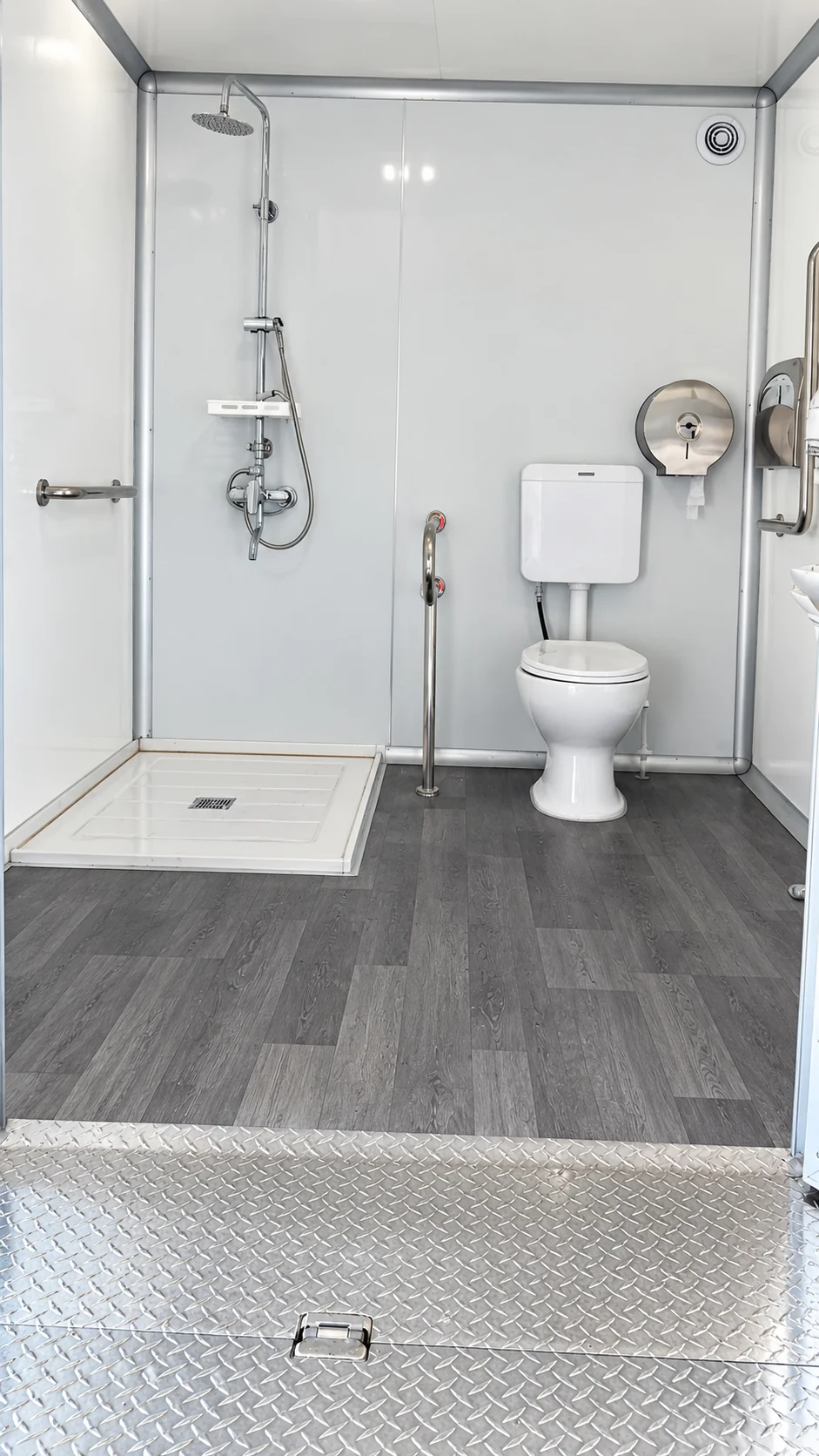 Larger shower-restroom trailer room with grab bars, toilet and open shower floor