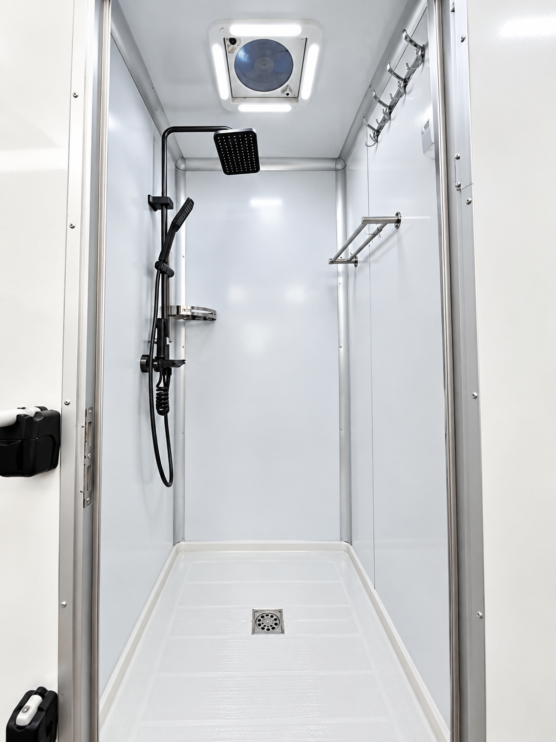 Interior of a mobile shower trailer with a private shower stall, shower fixtures and floor drain